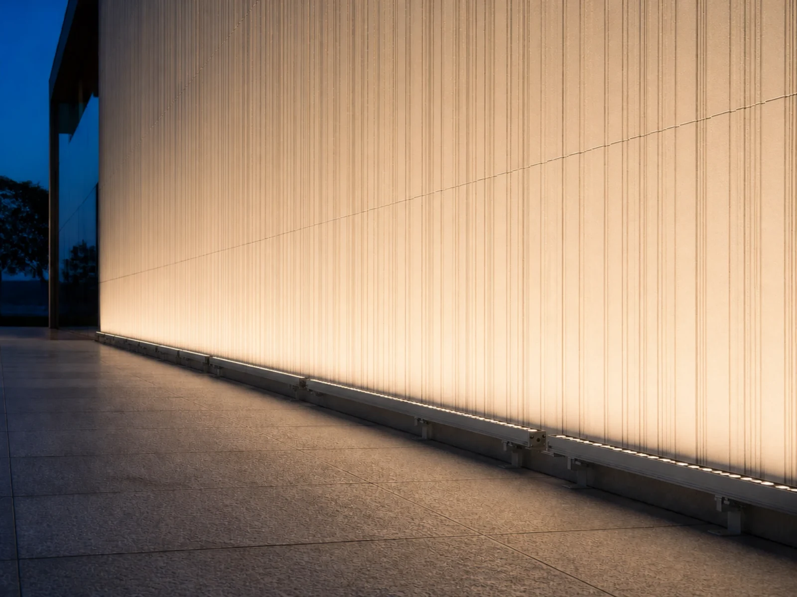 Outdoor linear wall washing across a textured architectural facade